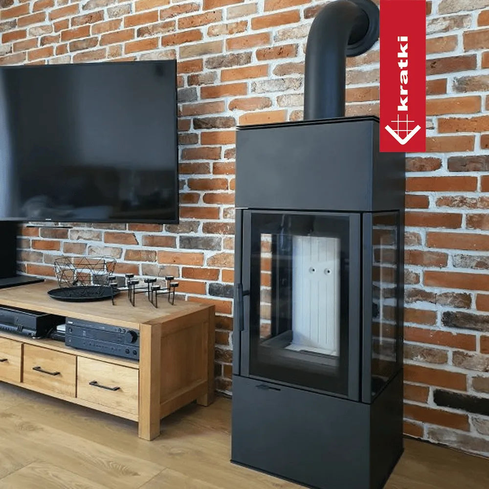 Kratki Thor houtkachel naast houten tv-meubel en flatscreen tegen bakstenen muur.