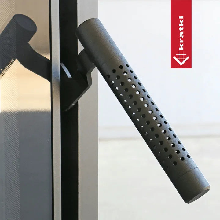 Kratki Titan Rond, een moderne, ronde, geperforeerde handgreep bevestigd aan een glazen deur.