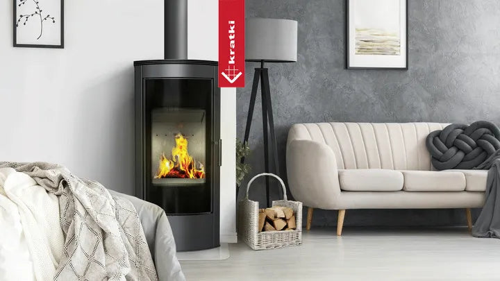Kratki Titan Rond houtkachel in moderne woonkamer met grijze bank en houten vloer.