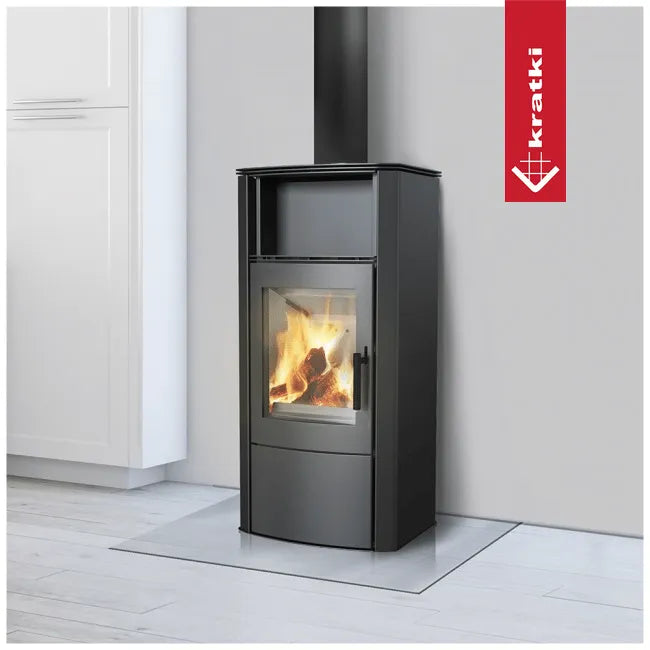 Zwarte houtkachel Kratki Proton met brandend vuur, geplaatst in een moderne, lichte woonkamer.