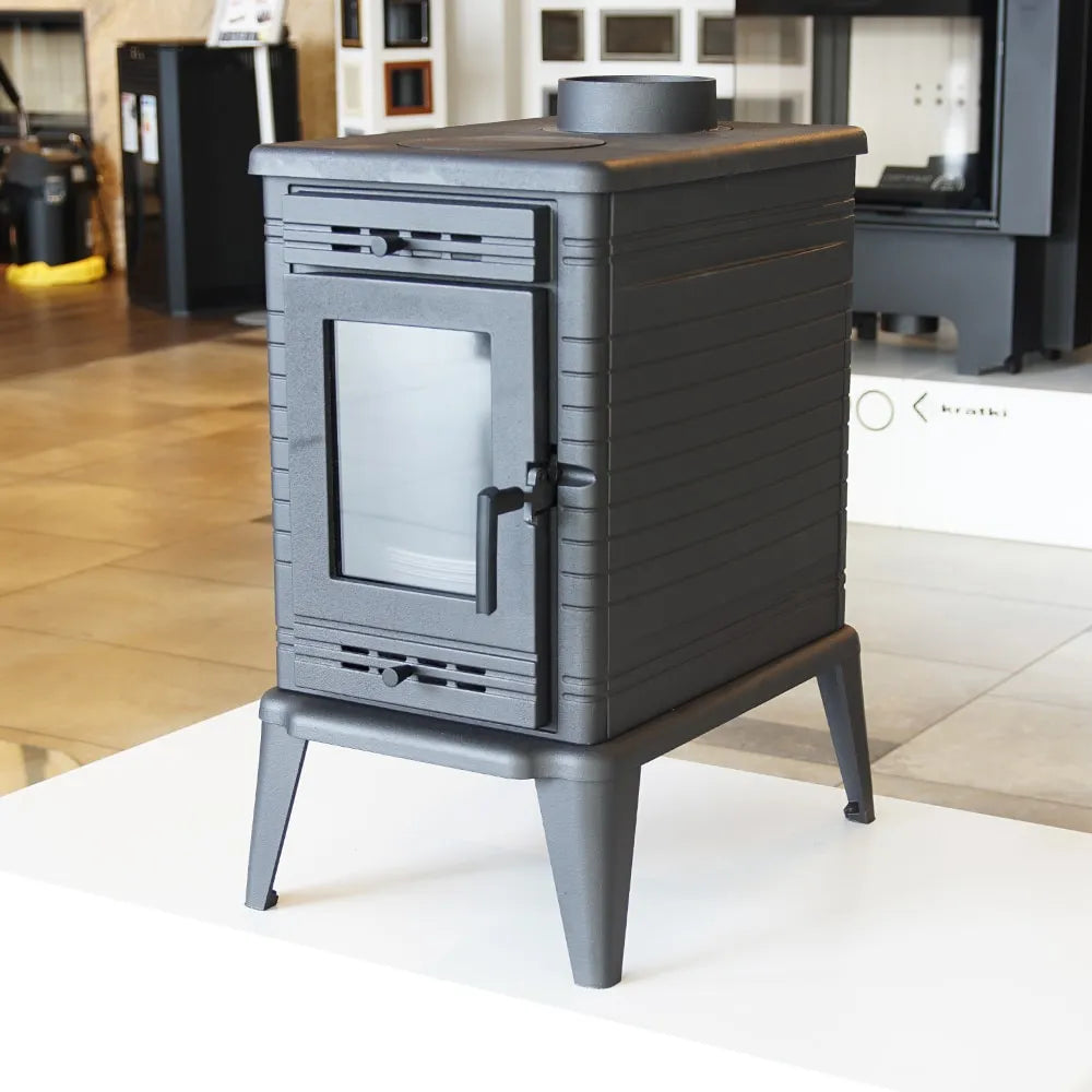 Zwarte, vrijstaande houtkachel Kratki K10 met glazen deur en vier poten in showroom.