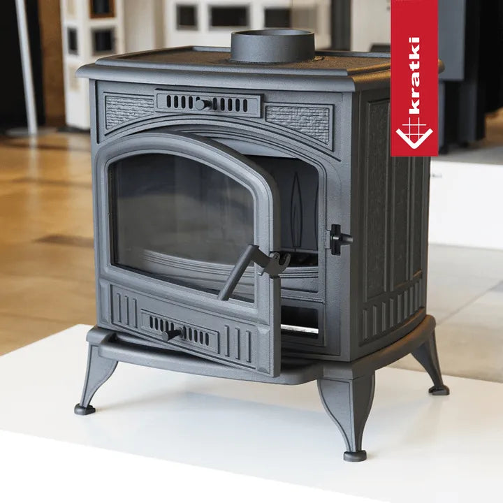 Kratki K6 houtkachel met open deur, geplaatst in een moderne showroom.