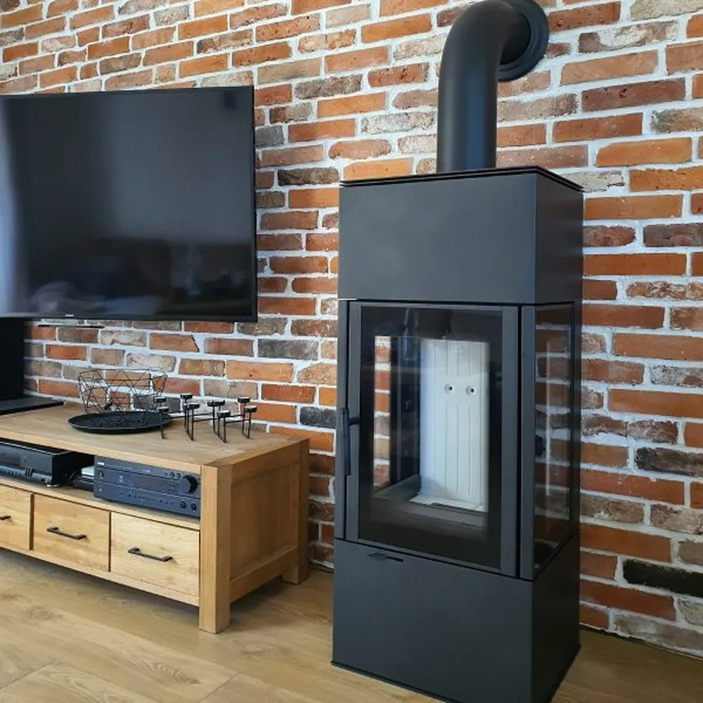 Kratki Thor houtkachel naast houten tv-meubel en flatscreen tegen bakstenen muur.