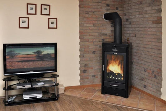 Verner 13/10.1 houtkachel in woonkamer bij bakstenen hoekwand, met brandend vuur