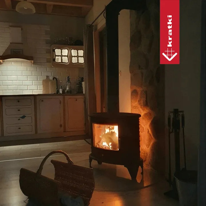 Gezellige keuken met brandende Kratki K8 houtkachel, rieten mand en rustieke inrichting.