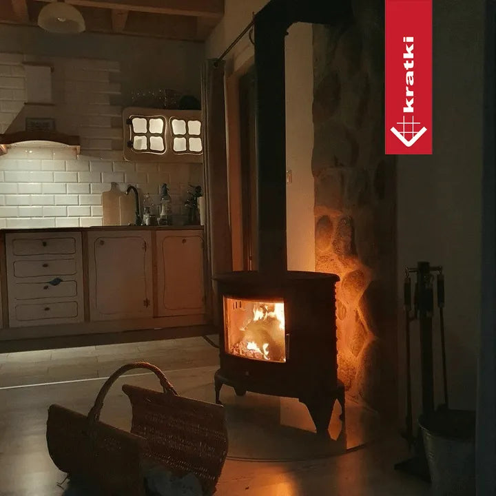 Gezellige keuken met brandende Kratki K8 houtkachel, rieten mand op de vloer.