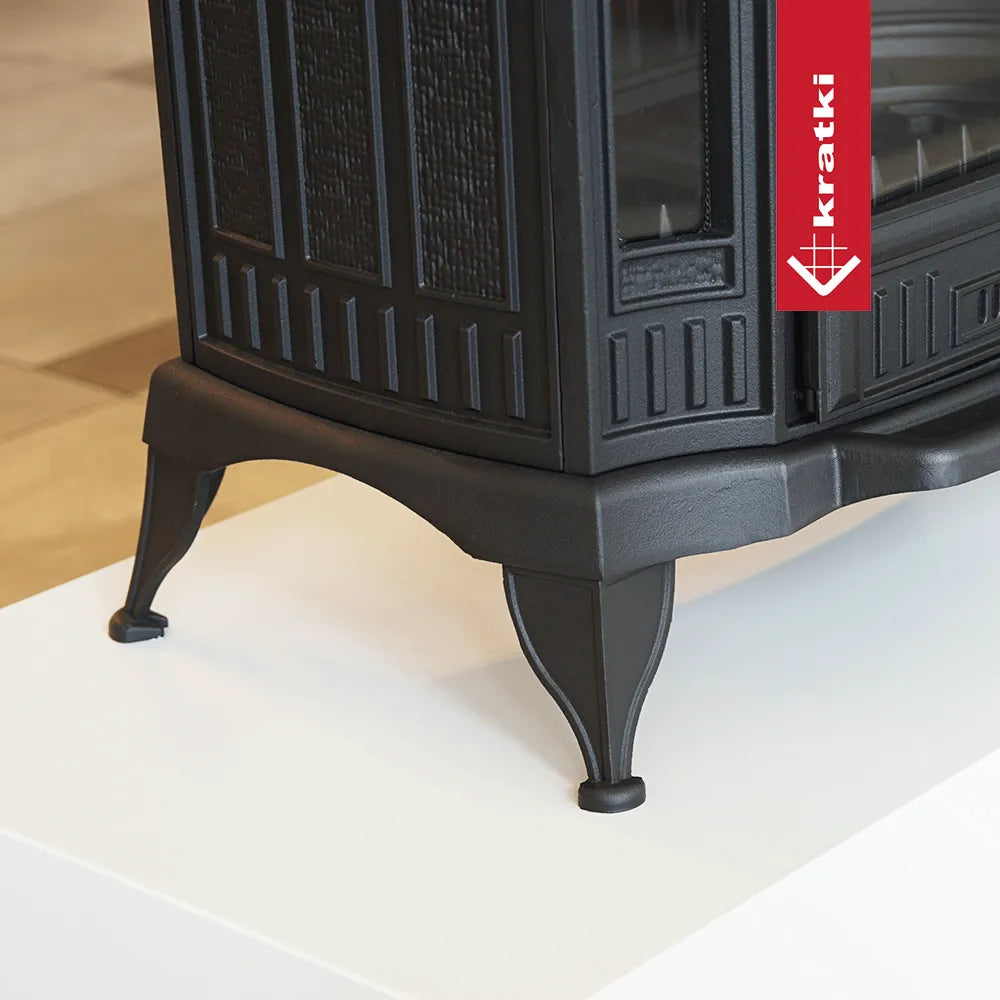 Zwarte gietijzeren houtkachel Kratki K9 met decoratieve poten en gedetailleerde zijpanelen.