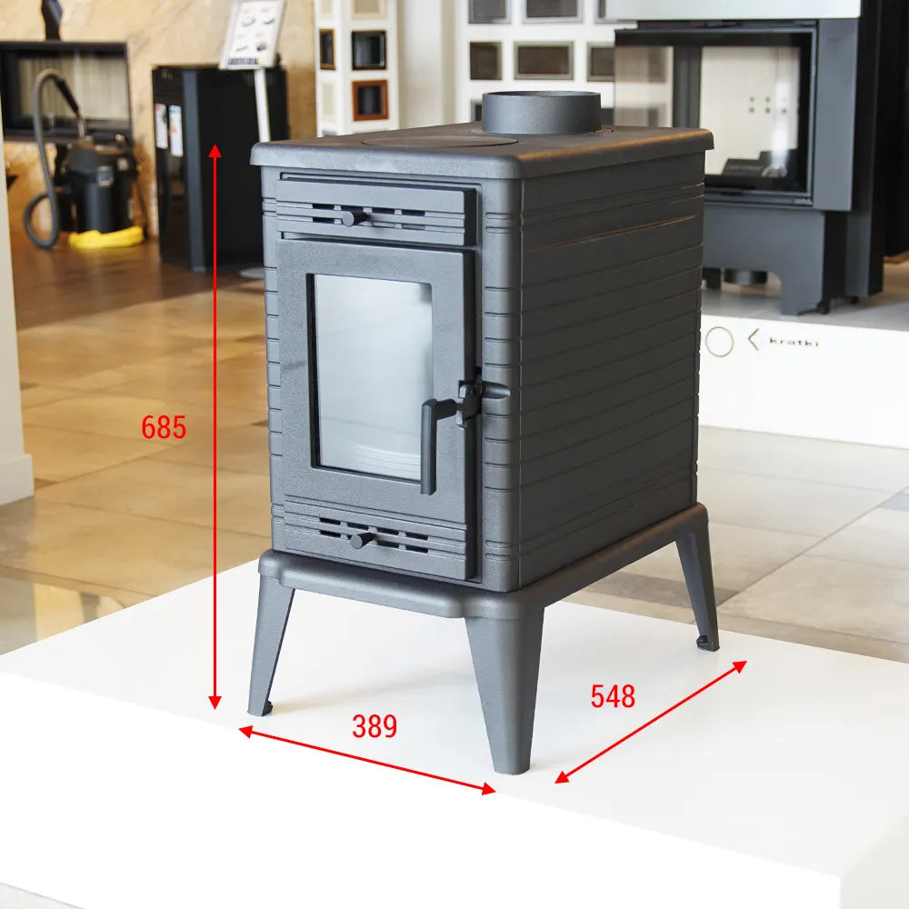 Zwarte Kratki K10 houtkachel met afmetingen, tentoongesteld in een showroom.