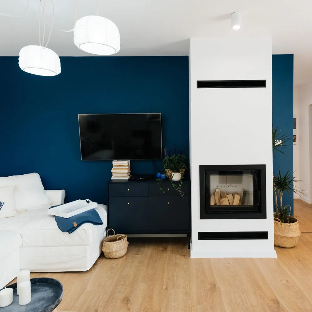 Moderne woonkamer met Kratki Lucy 12 kW Slim haard, blauwe muur en witte bank.
