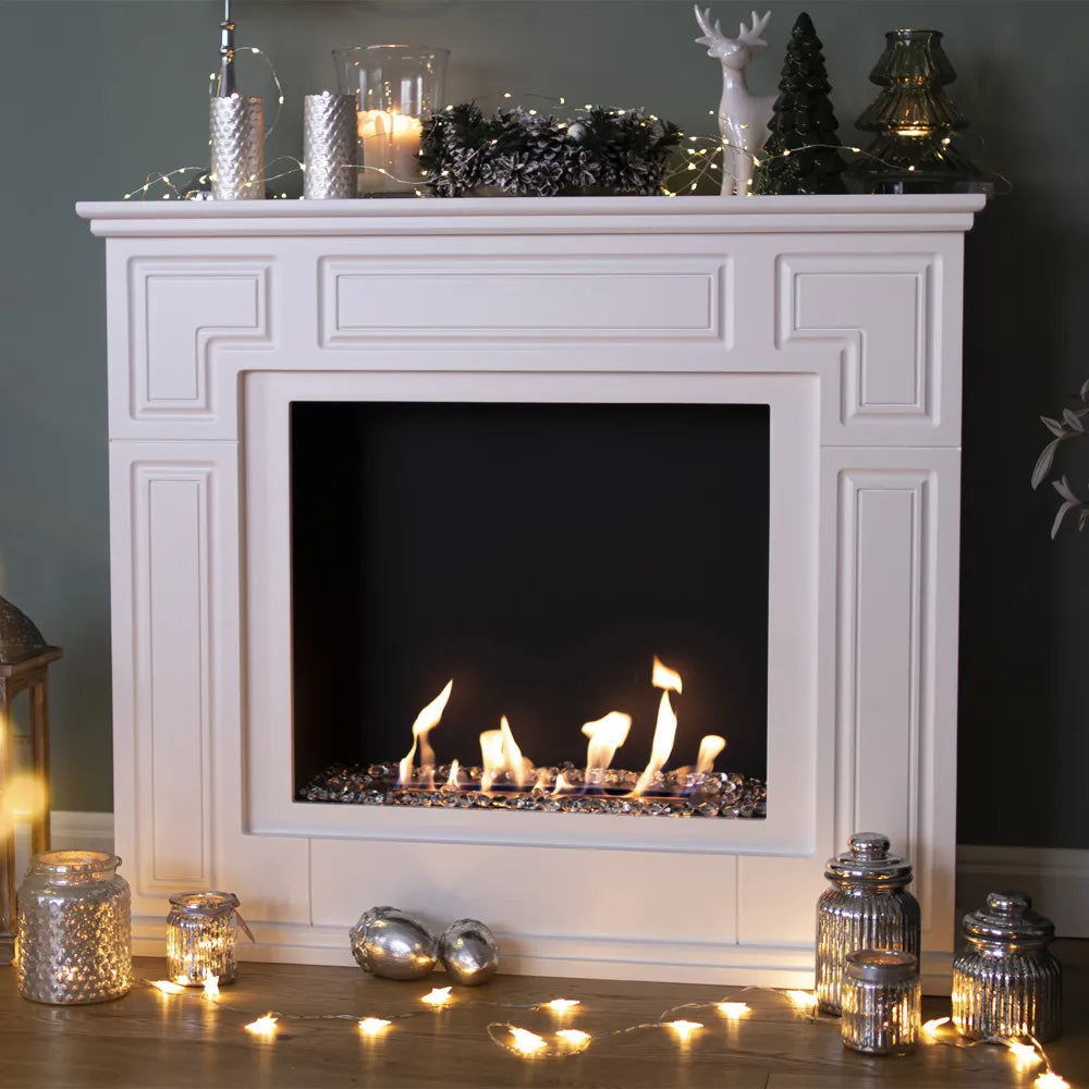 Witte Kratki March TÜV haard met decoratieve kerstverlichting en kaarsen op de schouw.