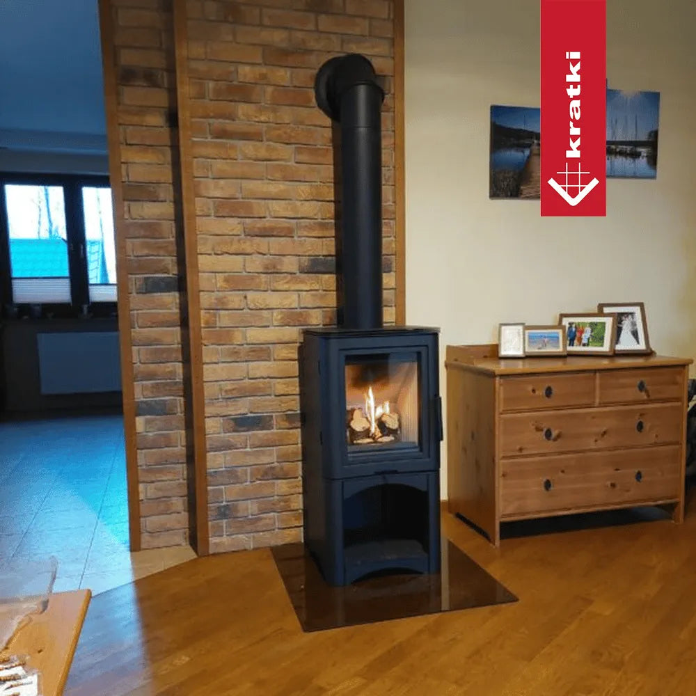 Kratki K5 Hoog houtkachel in een gezellige woonkamer met houten vloer en bakstenen muur.