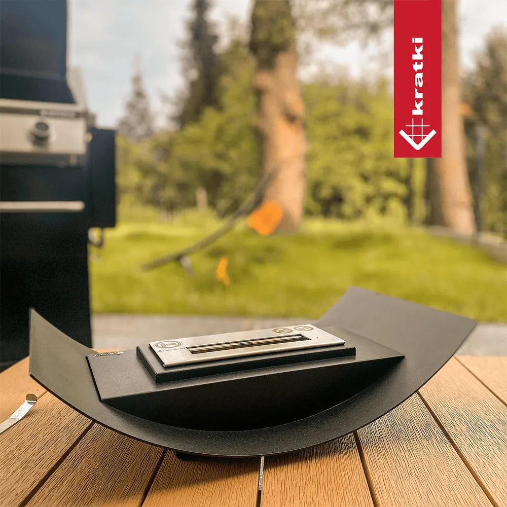 Kratki Biomisa TÜV op houten tafel, met groene tuin en barbecue op de achtergrond.