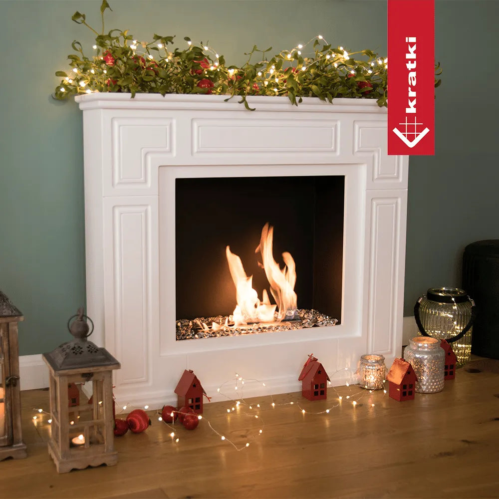 Kratki March TÜV haard met kerstdecoraties, lichtjes en lantaarns op een houten vloer.