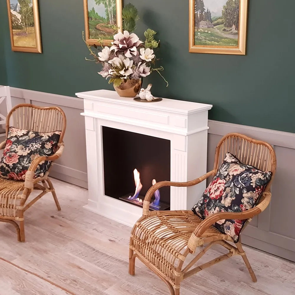 Kratki November TÜV haard in gezellige woonkamer met rotan stoelen en bloemendecoratie.