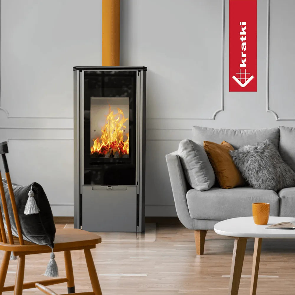 Kratki AB Enyo R Gas haard in moderne woonkamer met grijze bank en oranje accenten.