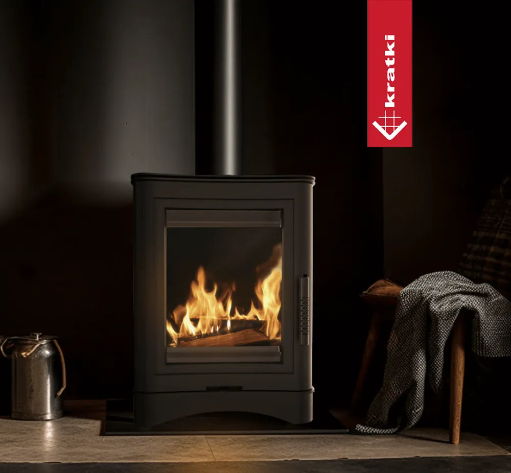 Kratki K5 houtkachel in een sfeervolle, donkere kamer met brandend vuur en gezellige inrichting.