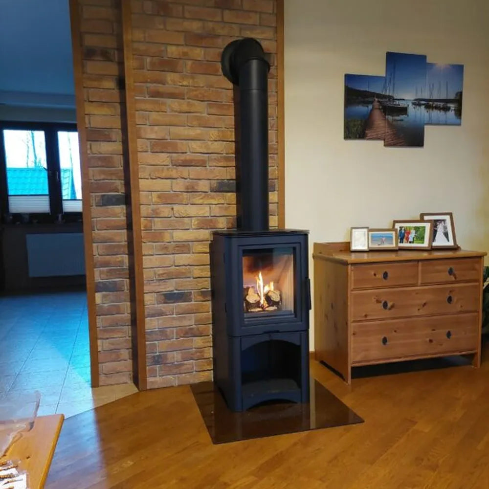 Kratki K5 Hoog houtkachel in een gezellige woonkamer met bakstenen muur en houten meubels.