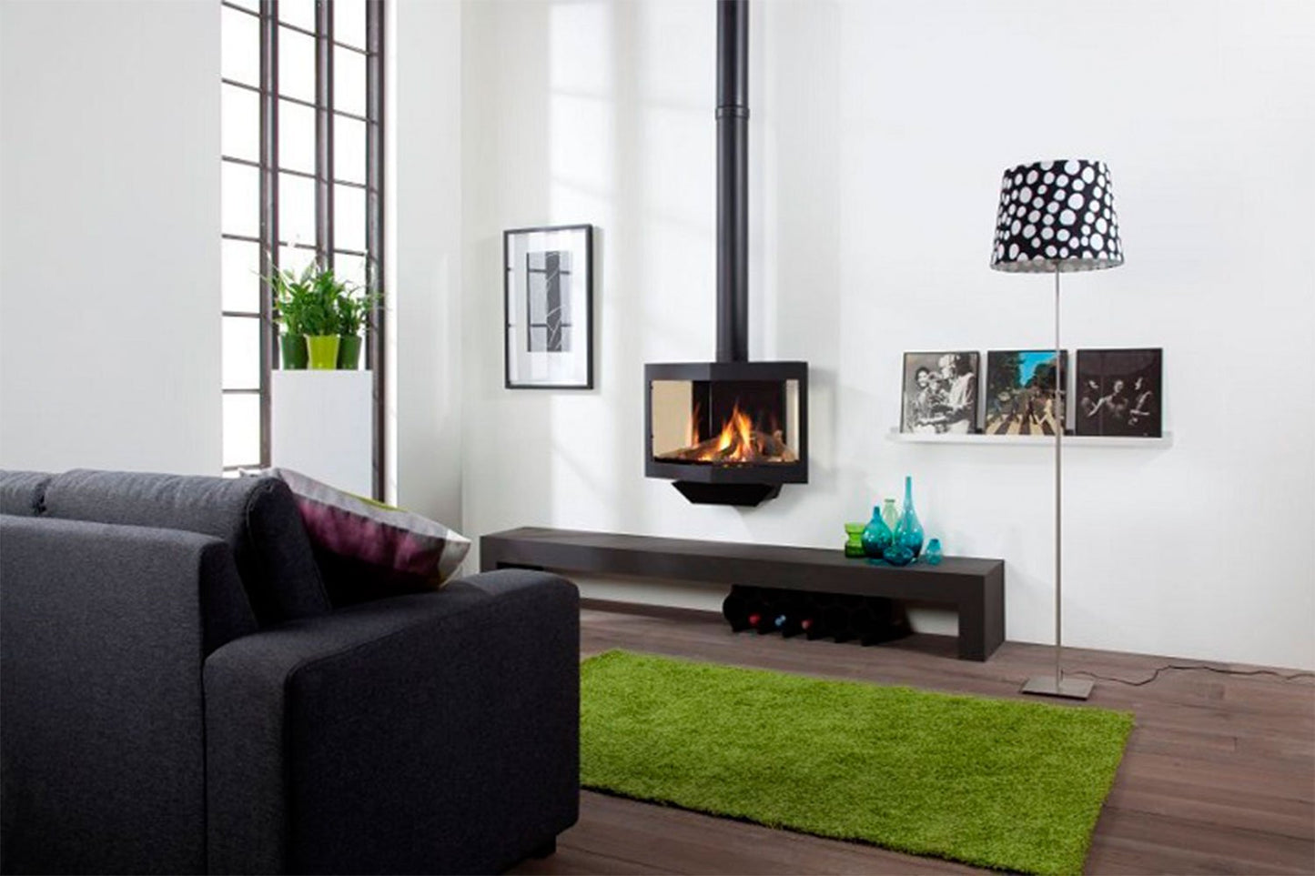 Woonkamer met HAVÉ Black Stealth gashaard, groene vloerkleed, grijze bank en moderne decoraties.