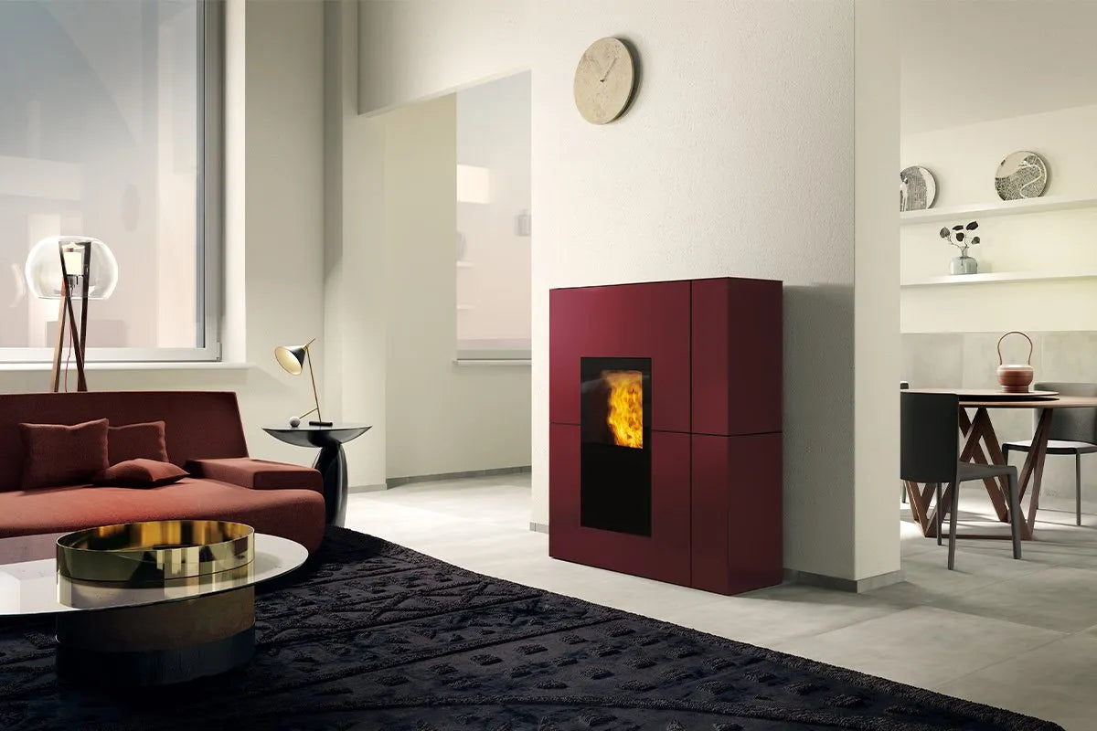 Moderne woonkamer met de Edilkamin Blade2 H 18 Up haard, rode bank en minimalistische inrichting.
