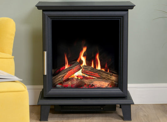 Charlton & Jenrick Luminosa kachel met brandend vuur in een woonkamer naast een gele fauteuil.