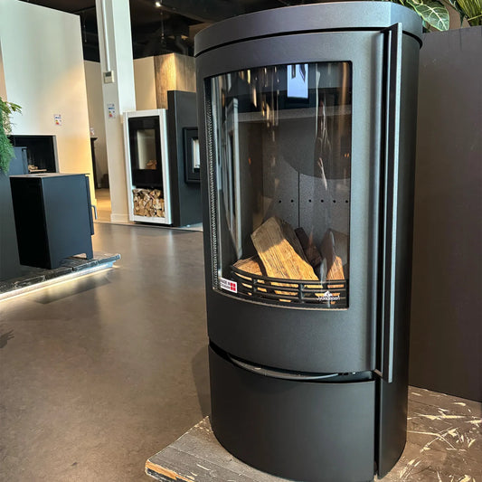 Zwarte houtkachel Jydepejsen Cozy Classic Low in een showroom met andere kachels op de achtergrond.