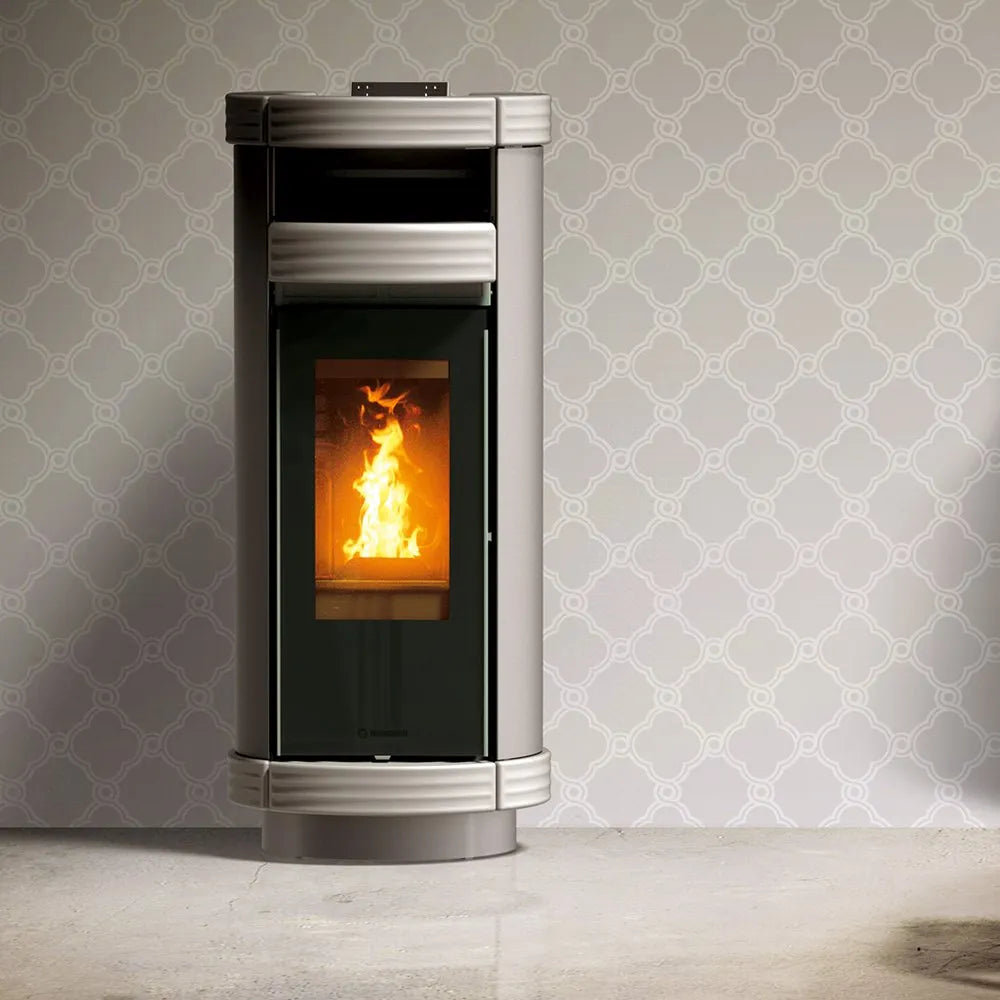 Thermorossi Dorica Plus Metalcolor pelletkachel met brandend vuur, tegen een sierlijk behang.