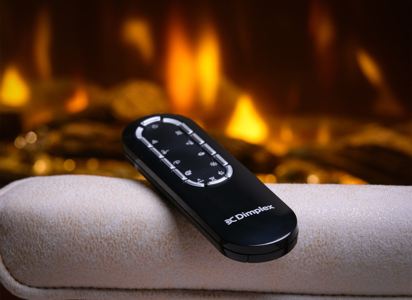 Afstandsbediening van de Dimplex Ignite Bold 50 op een beige oppervlak met vlammen op de achtergrond.