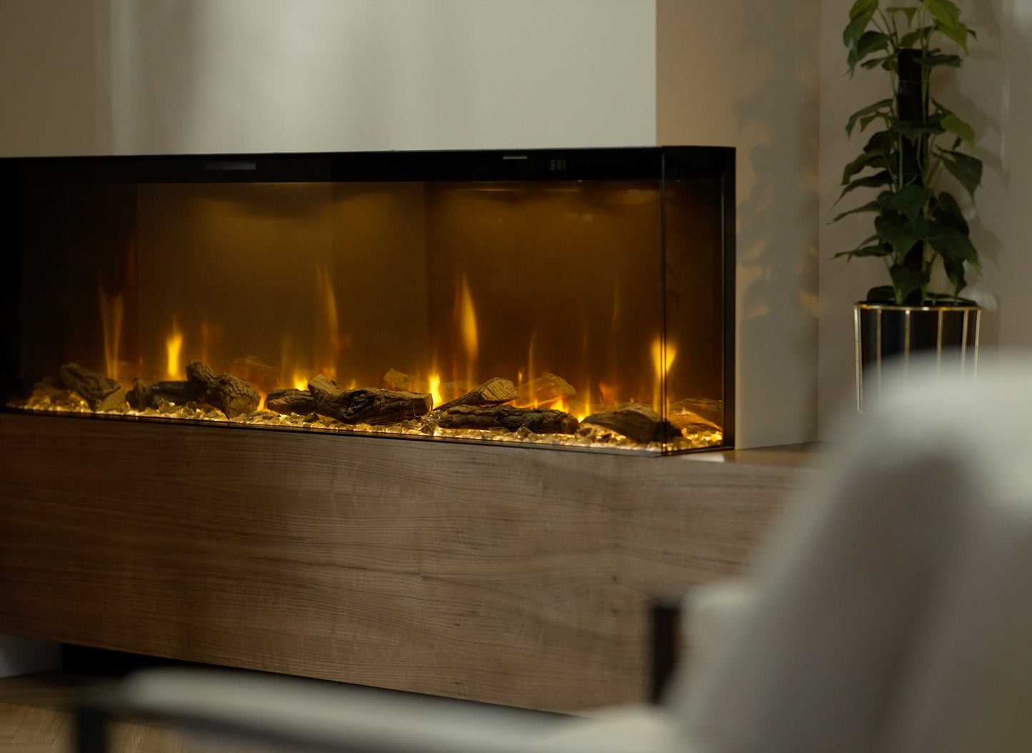 Dimplex Ignite Bold 74 elektrische haard met realistische vlammen en houtblokken, naast een plant.