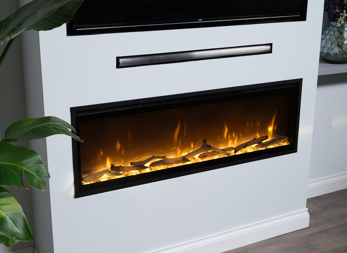 Dimplex Ignite Evolve 74 elektrische haard ingebouwd in een witte muur met brandende houtblokken.
