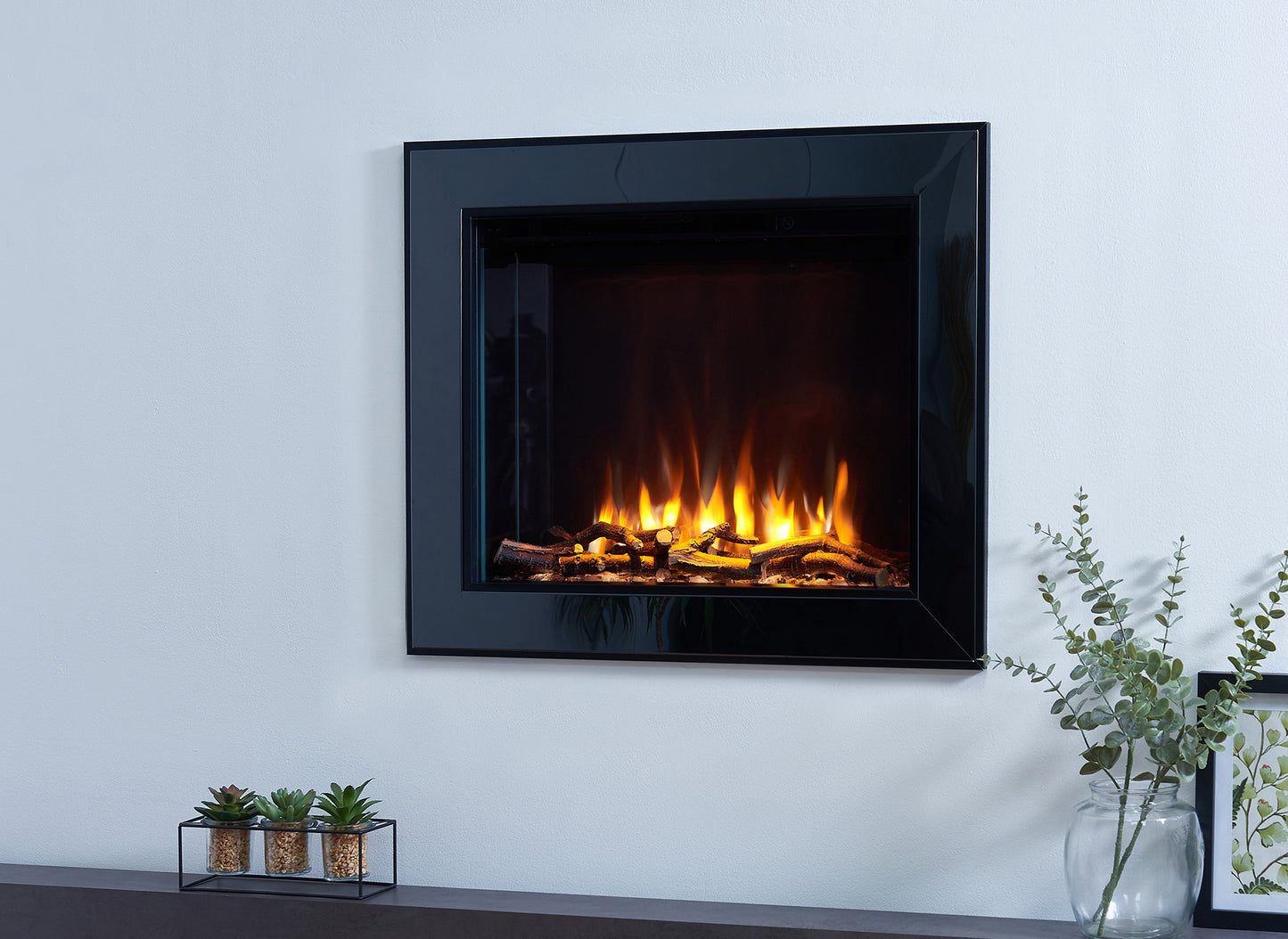 Charlton & Jenrick i-560e Slim elektrische haard met brandende houtblokken en decoratieve planten.