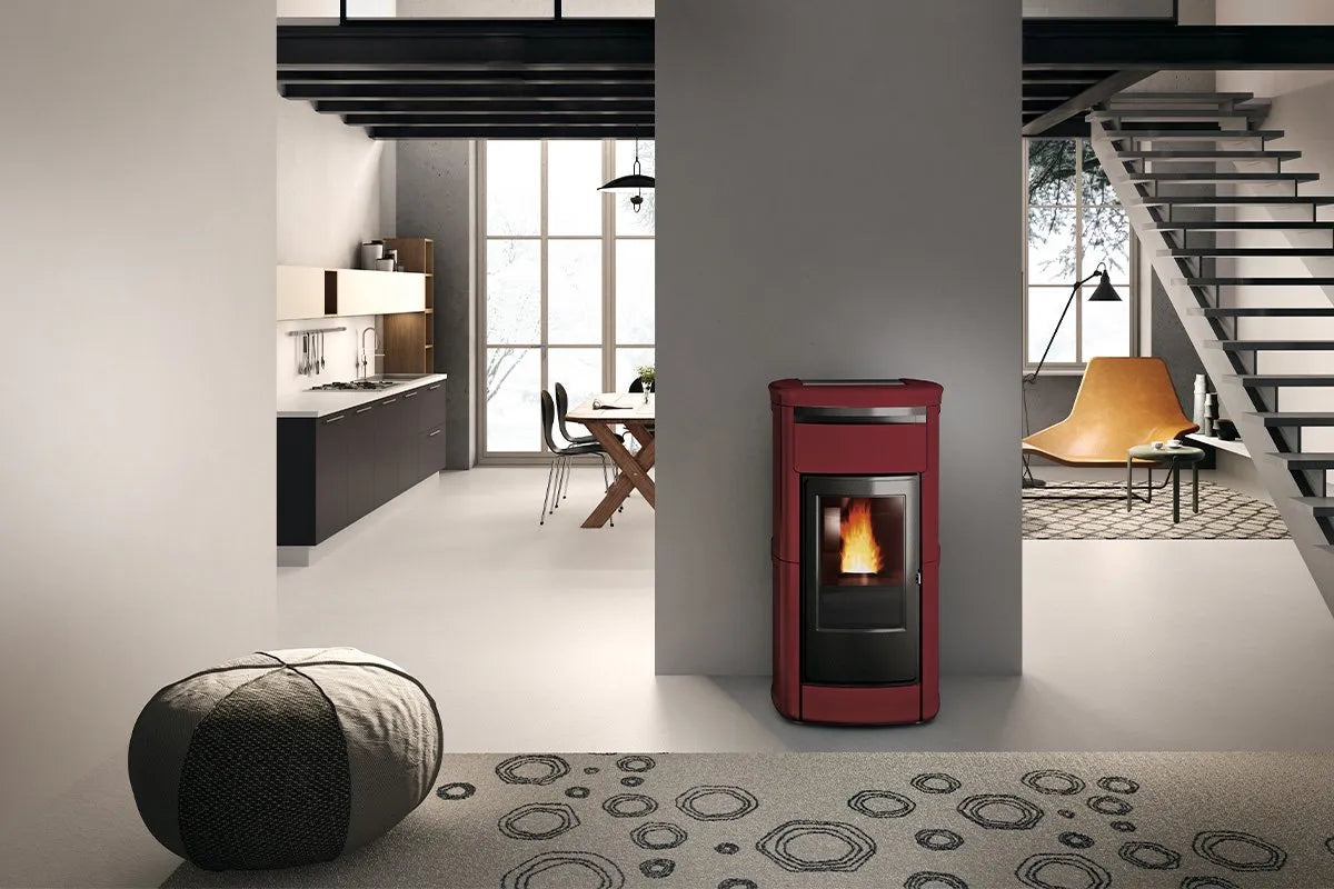 Moderne woonkamer met een Edilkamin Kira2 H 18 Up pelletkachel, naast een open keuken en trap.