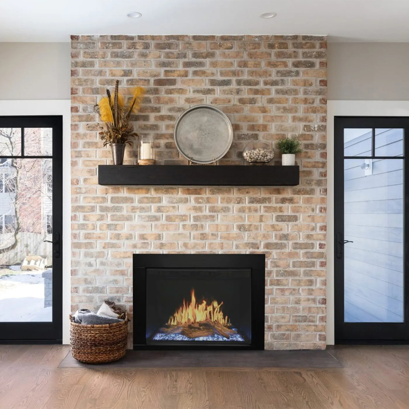 Bakstenen muur met Wanders Orion Traditional 30'' haard, zwarte plank en decoraties erboven.