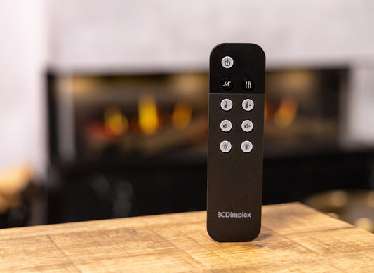Dimplex Opti-V Vista 130 I afstandsbediening op houten tafel, haard op achtergrond