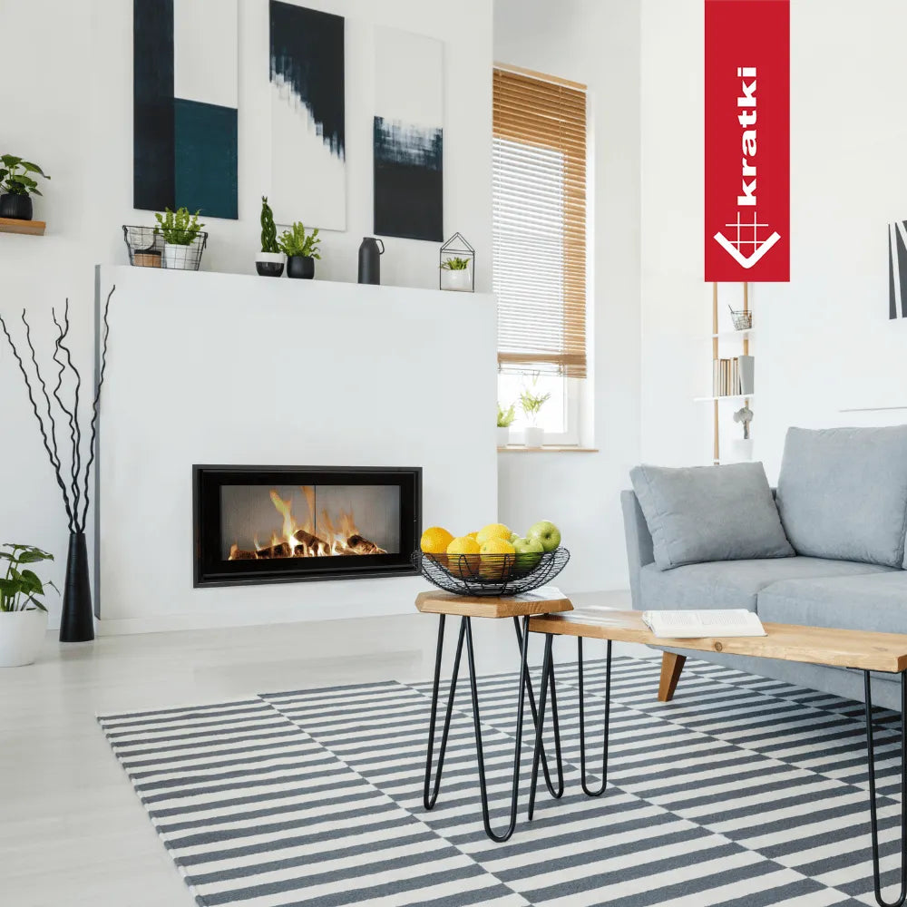 Moderne woonkamer met Kratki MB100 haard, grijze bank, fruitmand en zwart-wit gestreept tapijt.