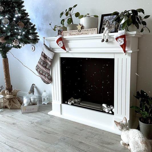 Witte Kratki November Rechts TÜV haard, versierd met kerstdecoraties en een kat op de vloer.