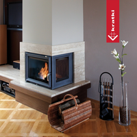 Kratki Zuzia hoekhaard met brandend vuur in een woonkamer, naast een houtmand en haardaccessoires.