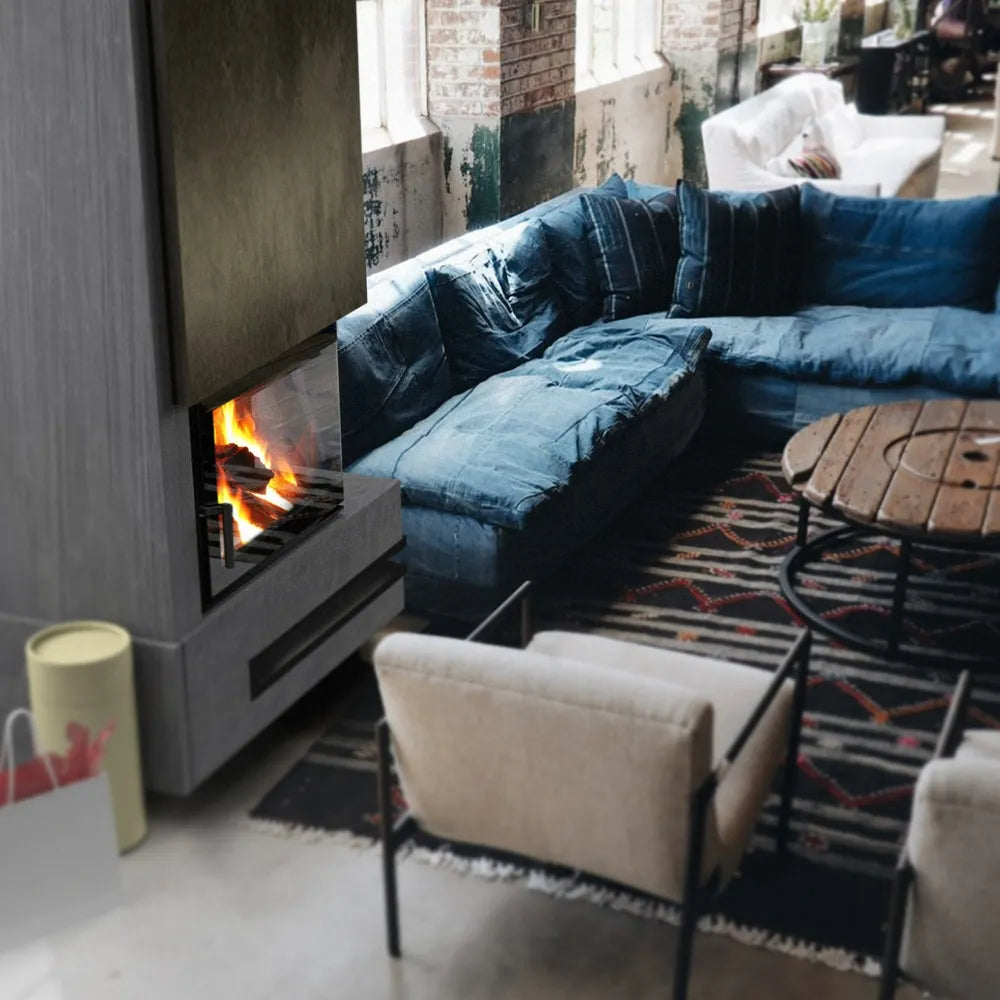 Kratki Lucy 12 kW Rechts in een gezellige woonkamer met blauwe hoekbank en ronde houten tafel.