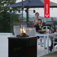 Kratki Patio Mini terrashaard met vlammen naast eettafel buiten