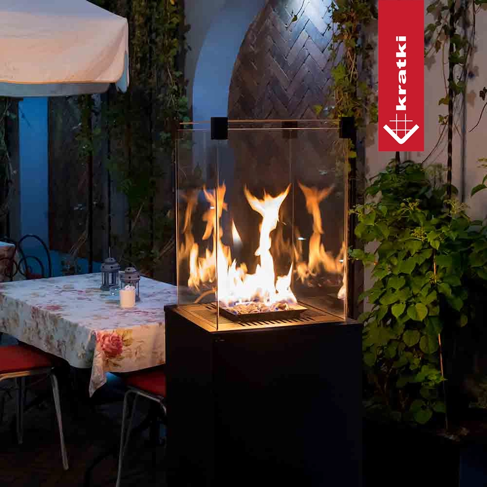 Krátki Patio Mini buitenhaard met vlammen op een terras naast een gedekte tafel
