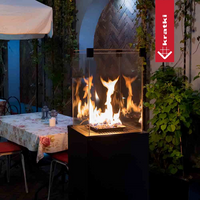 Krátki Patio Mini buitenhaard met vlammen op een terras naast een gedekte tafel
