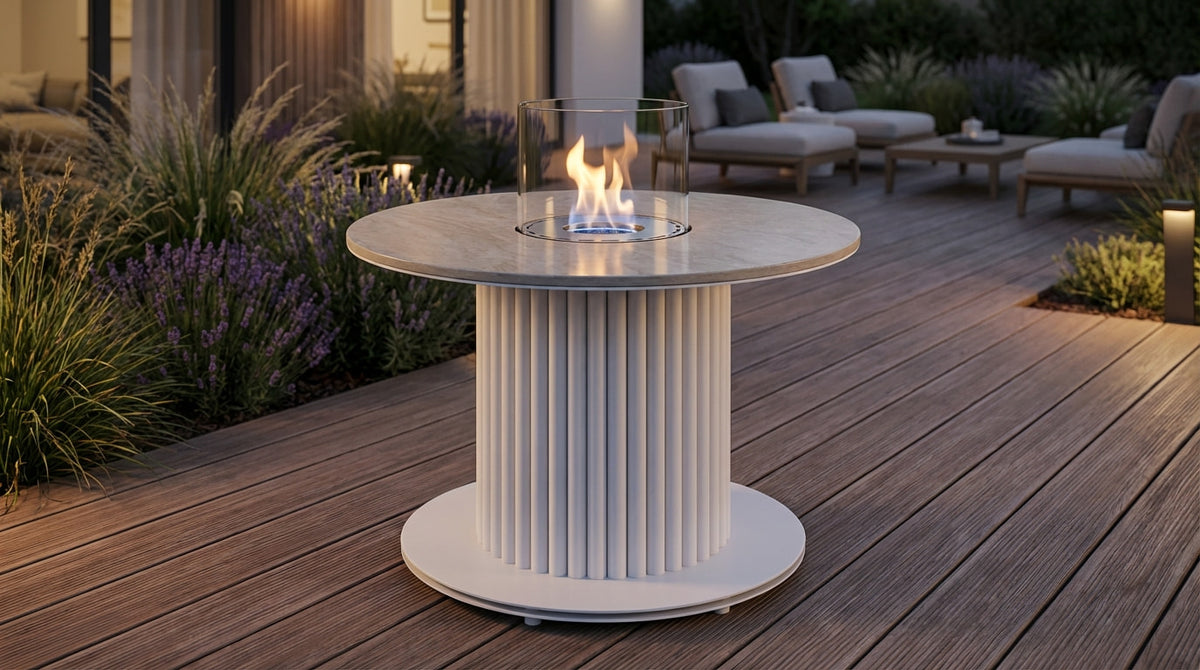 Balstil Table Core vuurtafel met vlam, glazen windscherm en ronde tafelbladen op een terras.