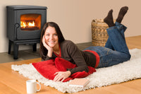 Dovre 325CB houtkachel in woonkamer met brandend vuur en vrouw op vloerkleed