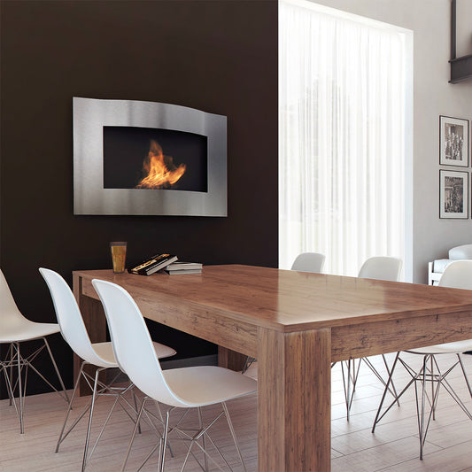 Moderne eetkamer met Kratki Lima TÜV haard aan de muur en houten tafel met witte stoelen.