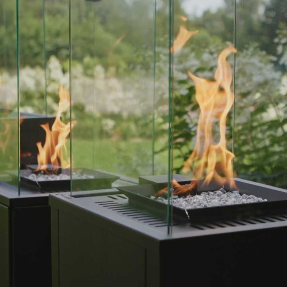Kratki Patio vuurhaard met vlammen in glazen ombouw, in een tuin