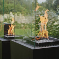 Kratki Patio vuurhaard met vlammen in glazen ombouw, in een tuin