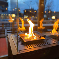 Kratki Patio Mini met brandende vlammen op een terras bij avondlicht