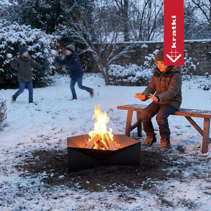 Kratki Gamma vuurschaal met brandend hout in besneeuwde tuin