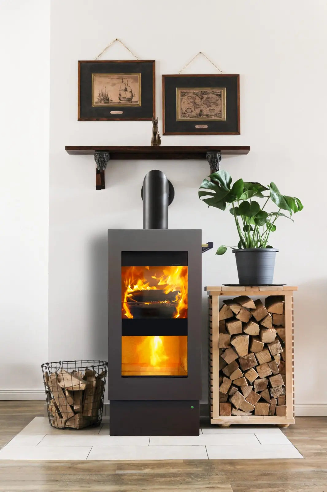 Xeoos Patagonia x8 Blue Stahl houtkachel met brandend vuur, naast houtopslag en plant.