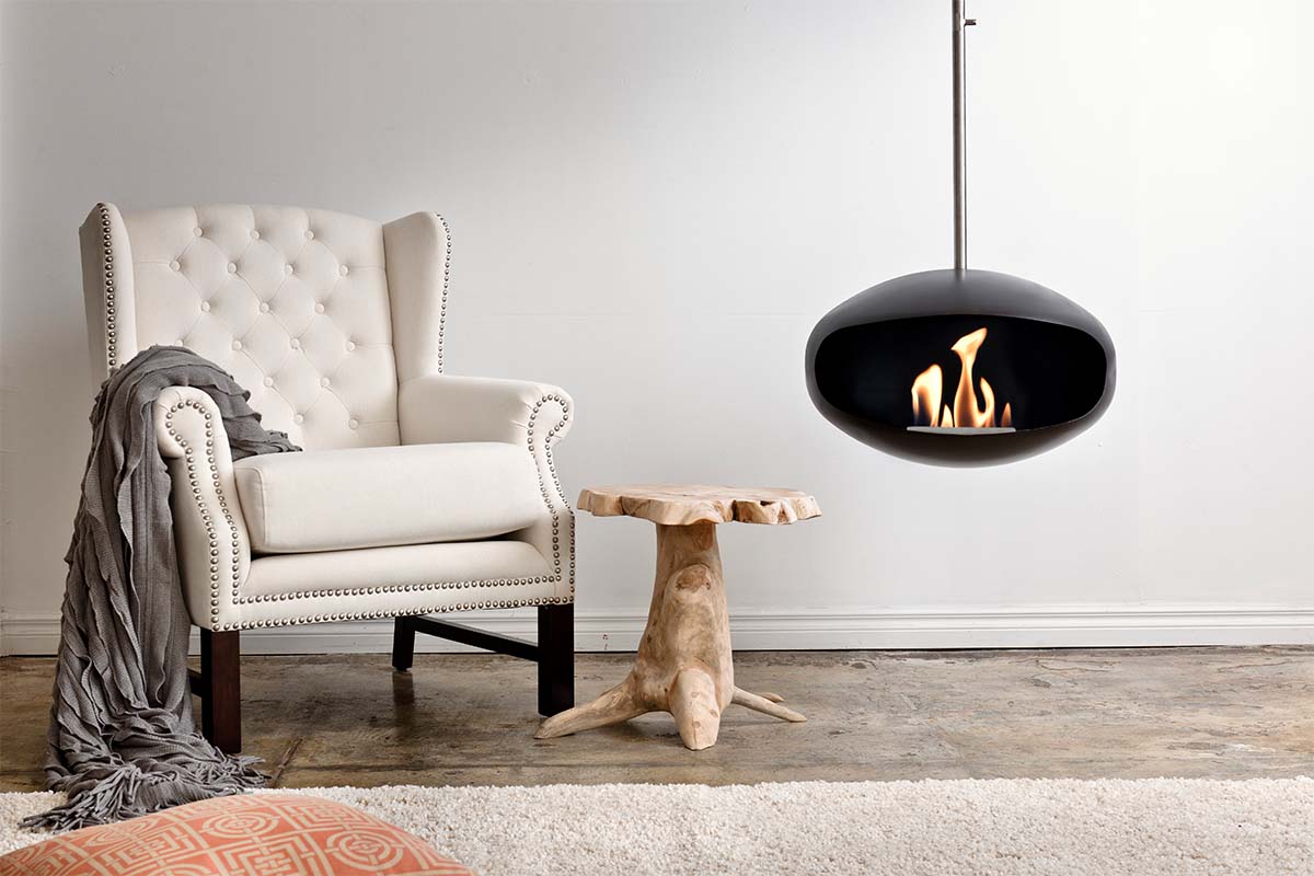 Cocoon Fires Aeris zwart hanghaard in woonkamer naast fauteuil