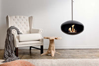 Cocoon Fires Aeris zwart hanghaard in woonkamer naast fauteuil